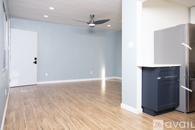 A spacious room with a ceiling fan and a built-in fridge.