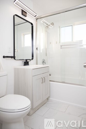 A white toilet sits next to a white cabinet with a mirror above it.