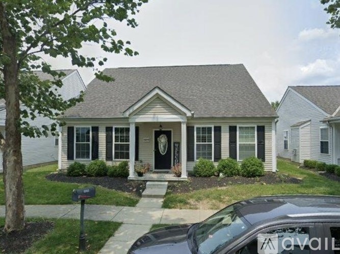 A house with a black front door and white siding is for sale.