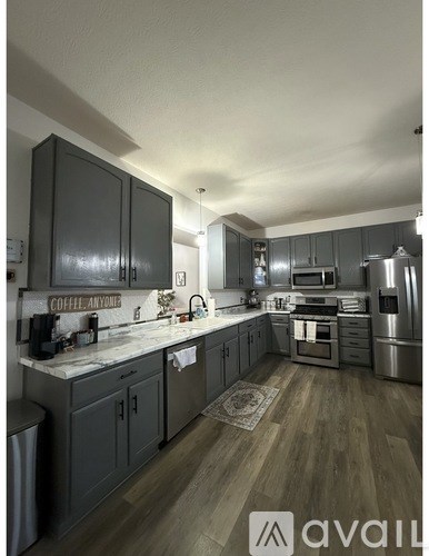 A kitchen with wooden floors and grey cabinets.