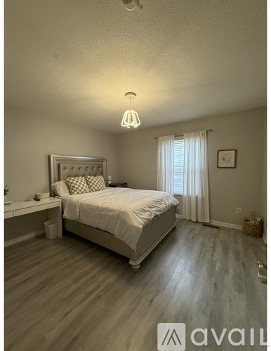 A bedroom with a bed, nightstand, and window.