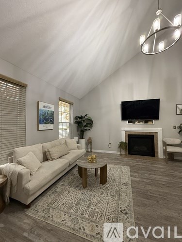A living room with a white couch, a coffee table, and a fireplace.