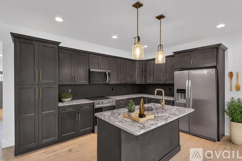 A kitchen with dark wood cabinets and a marble island.