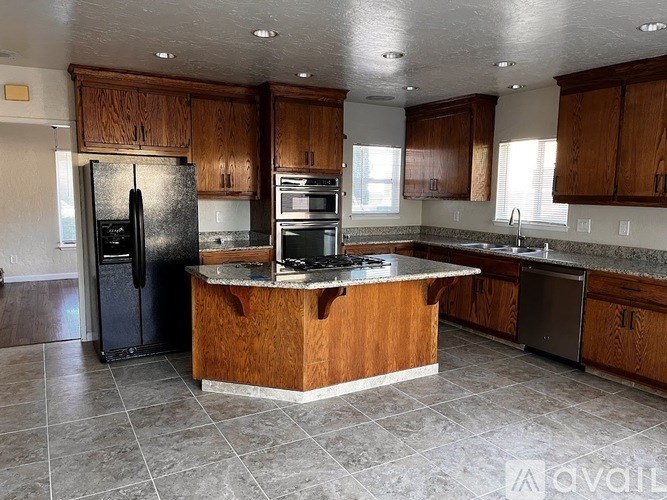 A kitchen with a black refrigerator and wooden cabinets.