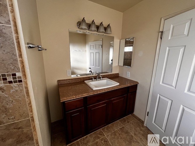 A bathroom with a sink, mirror, and a closed white door.