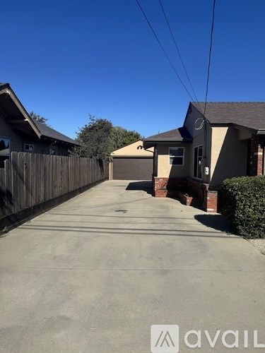 A residential street with houses on either side and a clear blue sky above.