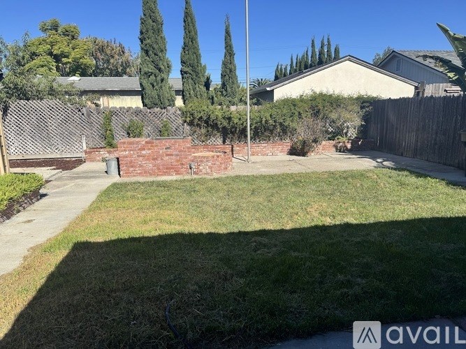 A backyard with a lawn, a fence, and a tree.