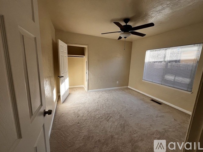 A room with a ceiling fan and carpeted floor.