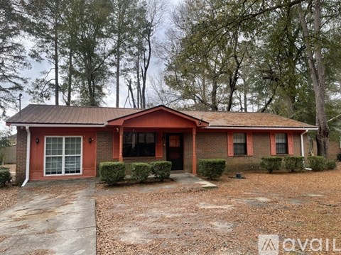 A red brick house with a porch and a driveway in front.