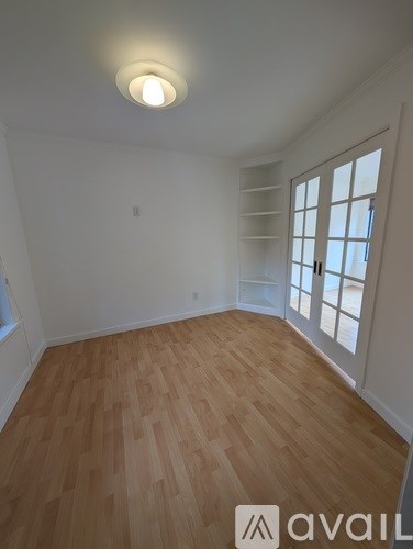 A room with wooden flooring and a window with white shutters.