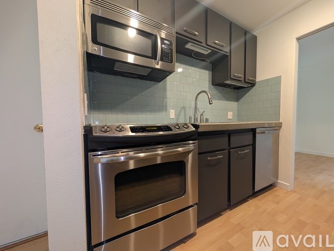 A modern kitchen with stainless steel appliances and a wooden floor.
