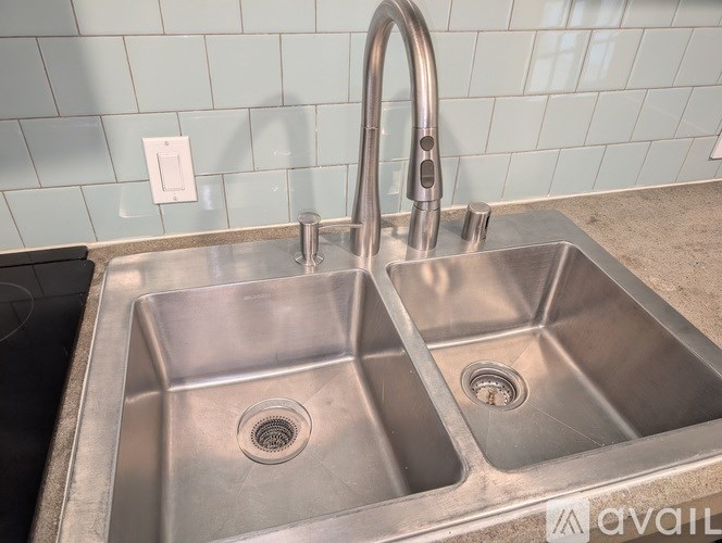 A stainless steel double sink with a faucet and a drain in the middle.