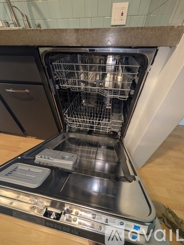 An open dishwasher with the door open and the rack visible.