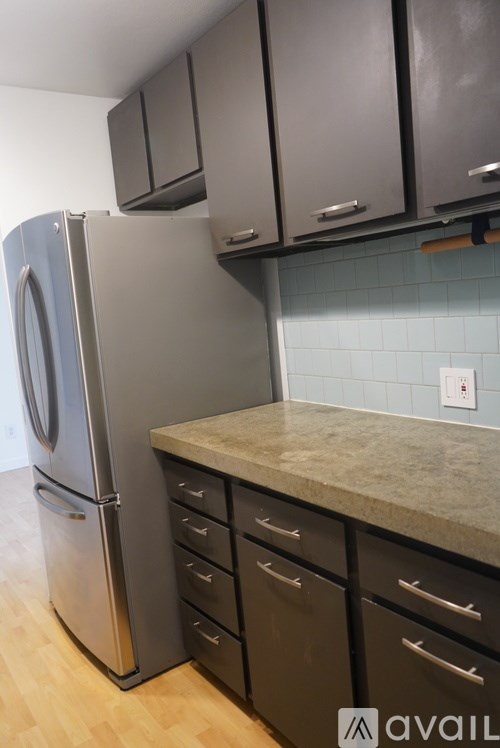 A kitchen with a stainless steel refrigerator and black cabinets.