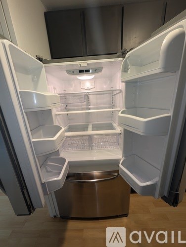 A white refrigerator with its door open and a stainless steel ice maker.