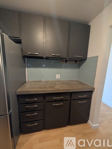 A kitchen with a refrigerator, cabinets, and drawers.