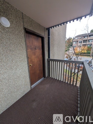 A balcony with a brown door and a metal railing.