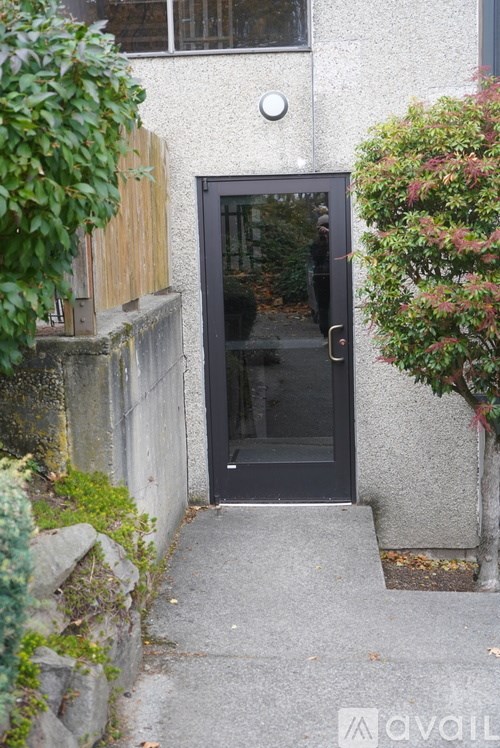 A black door is in a white building with a step leading up to it.