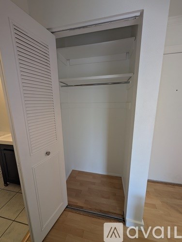 A white closet with a mirror and shelves is open.