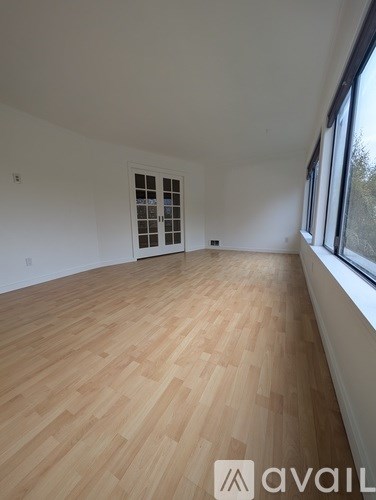 A room with wooden flooring and a window on the right side.