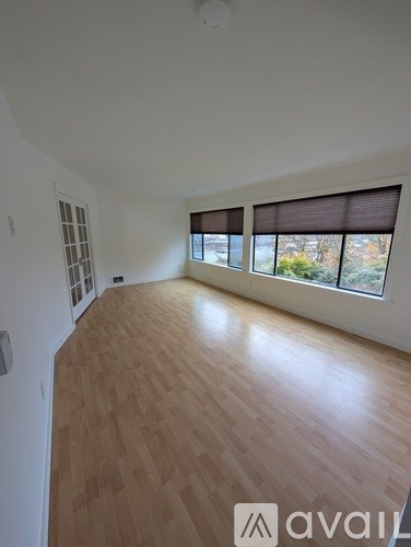 A room with wooden flooring and a window with blinds.