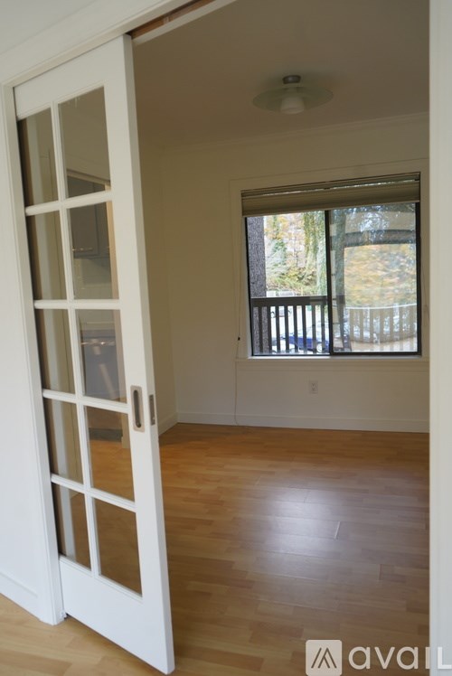 A room with a white door and wooden floor.