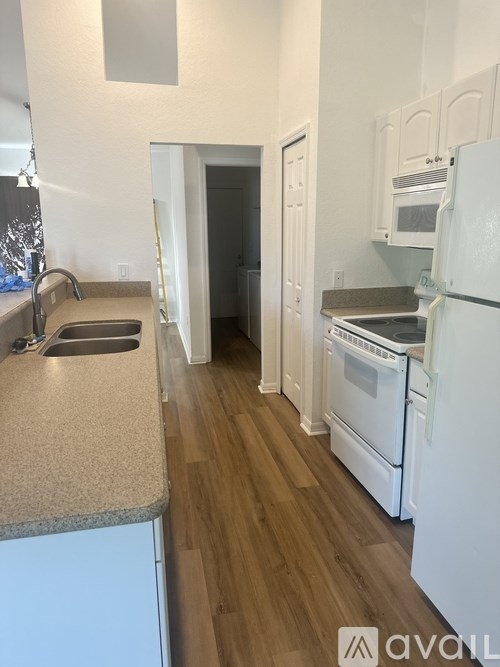 A kitchen with white appliances and wooden floors.