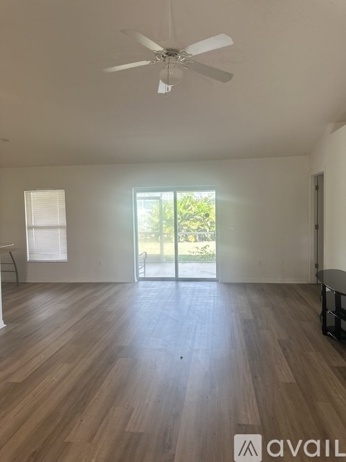 A room with a ceiling fan and wooden flooring.