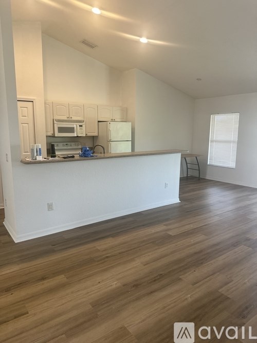 A kitchen with white appliances and wooden floors.