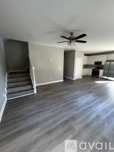 A spacious room with a staircase and a ceiling fan.