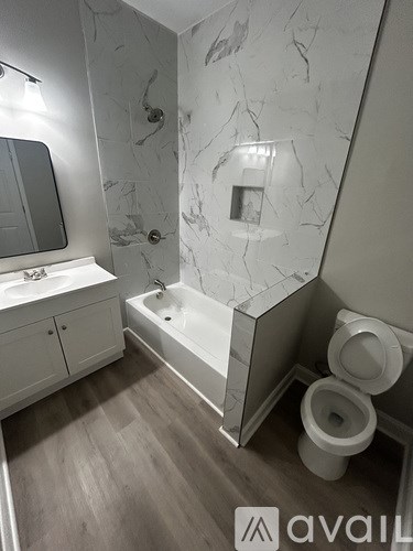 A bathroom with a marble wall and a white bathtub.