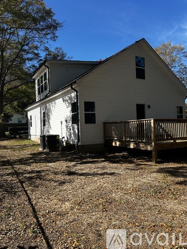 A white house with a porch and a tree in front.