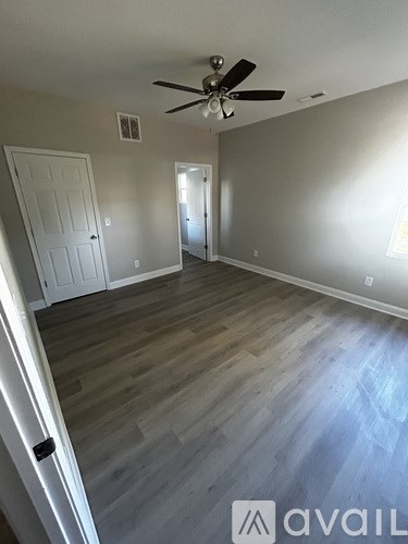 A room with a ceiling fan and light fixture, two doors, and a wooden floor.