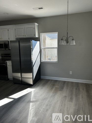 A kitchen with a stainless steel refrigerator and wooden flooring.