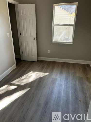 A room with a white door and a window with a view of a house.