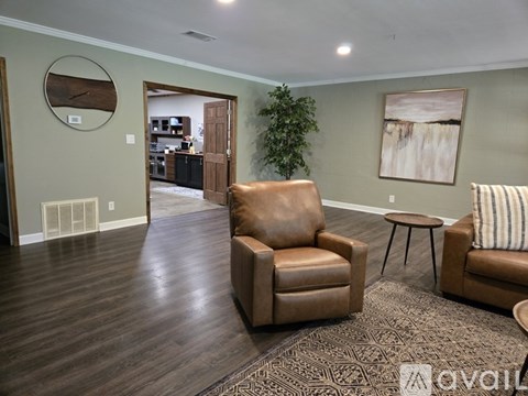 A living room with brown leather chairs and a round mirror on the wall.