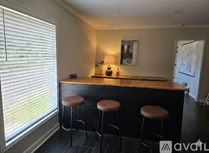 A bar area with a wooden counter and three stools.