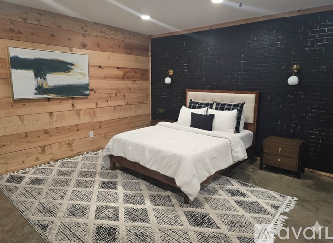 A bedroom with a wooden headboard and a black and white rug.