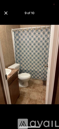 A bathroom with a toilet and a shower with a blue tile wall.
