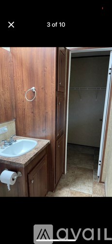 A bathroom with a sink, toilet paper, and a towel rack.