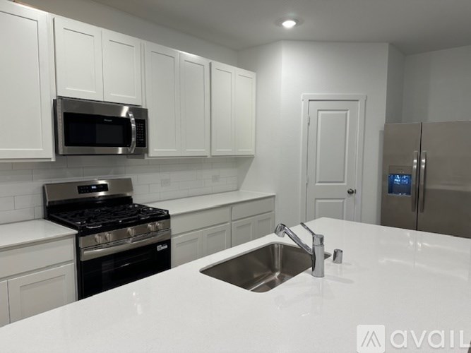 A kitchen with white cabinets and a stainless steel refrigerator.