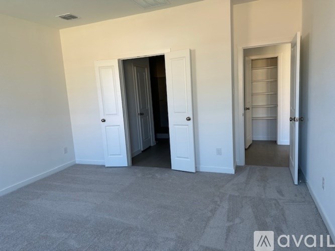 A room with a carpeted floor and two doors, one of which is open.