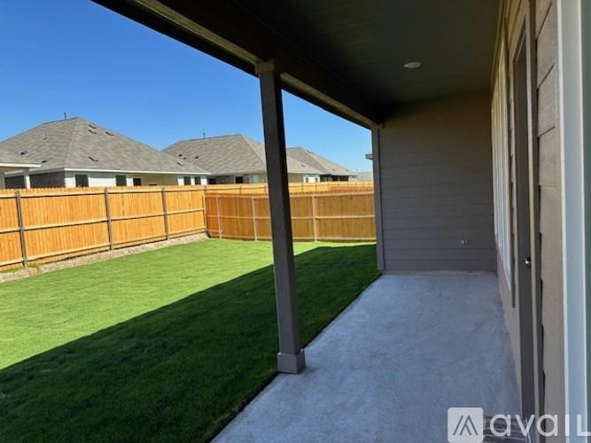 A backyard with a wooden fence and a green lawn.