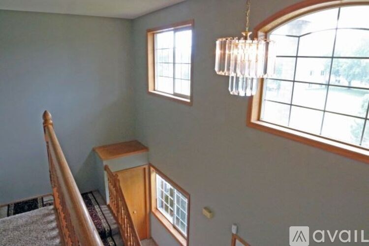 A chandelier hangs over a staircase with a window on the side.