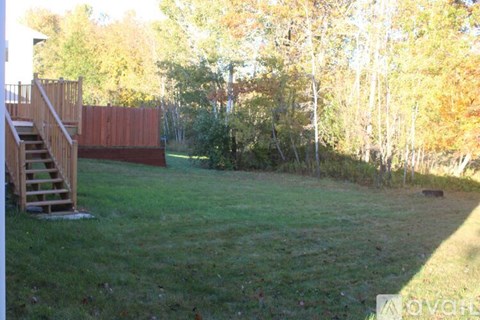 A backyard with a wooden deck and a grassy area.