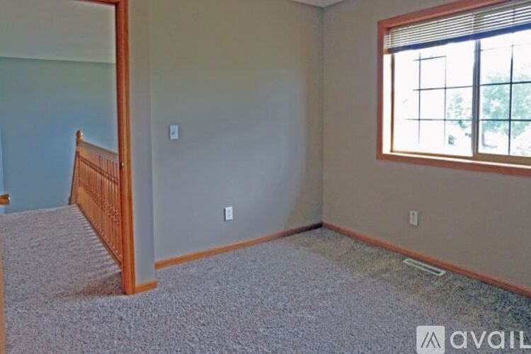 A room with a carpeted floor and a window with blinds.