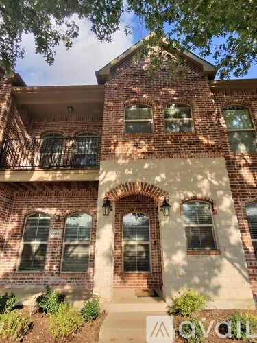A red brick house with a balcony on the second floor.