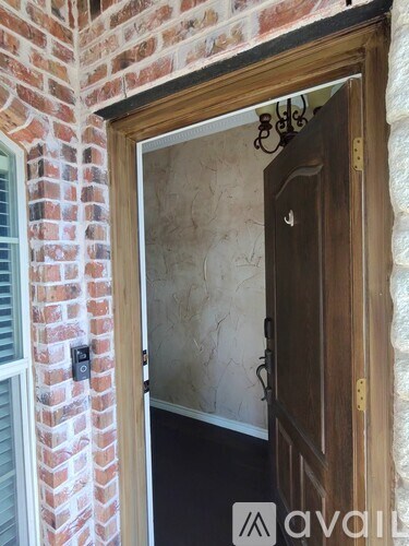 A doorway with a wooden door and a brick wall on the left.