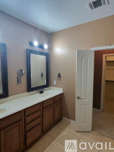 A bathroom with a sink, mirror, and wooden cabinets.