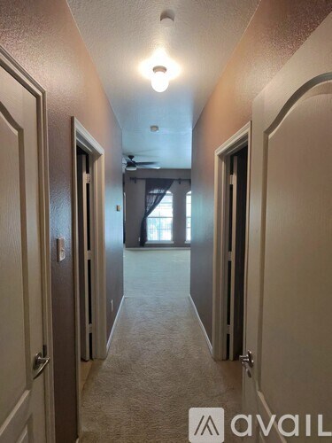 A hallway with a carpeted floor and doors on both sides.